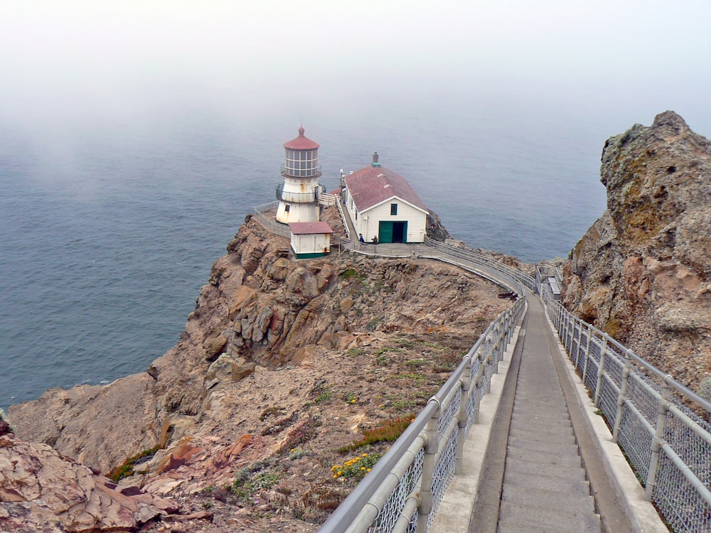 a lighthouse on a cliff with Point Reyes in the background