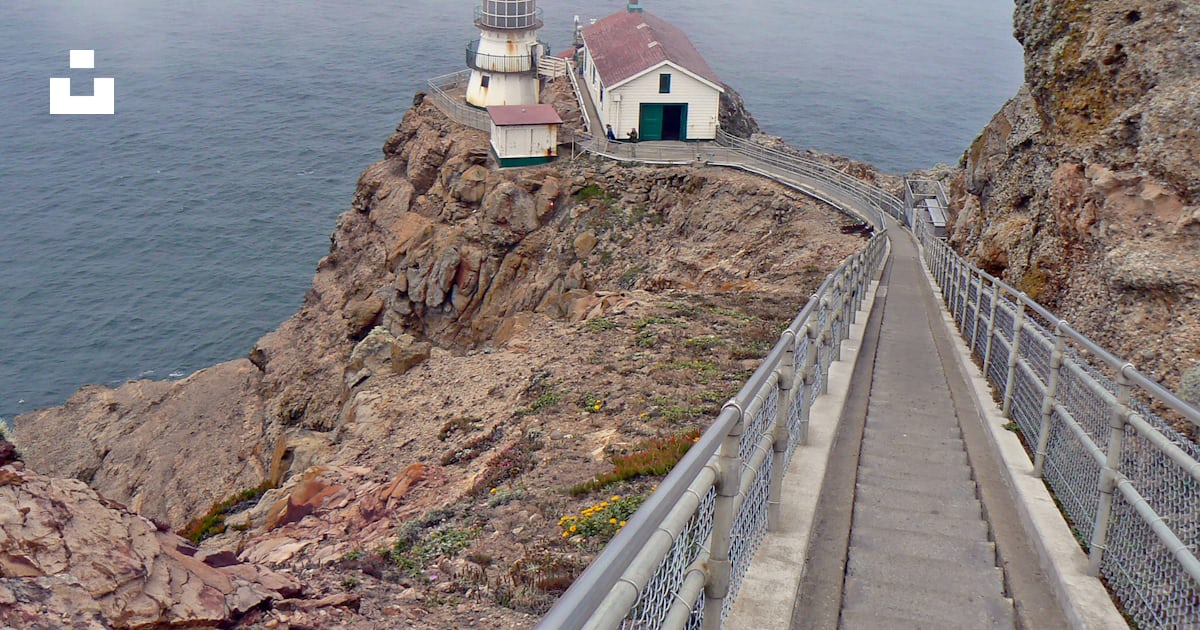 A lighthouse on a cliff with Point Reyes in the background photo – Free ...