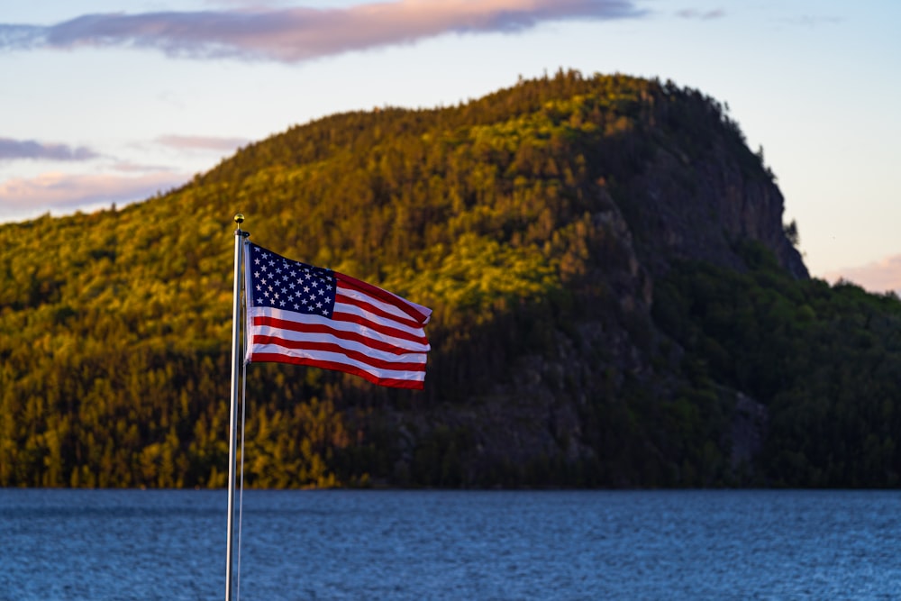 a flag on a pole in front of a body of water