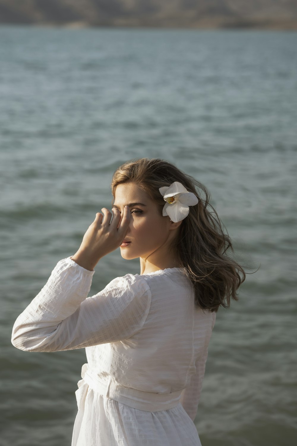 a person with a flower in the hair by the water