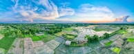 A panoramic view of the farmhouse grounds at sunset, highlighting the blend of livestock and crops.