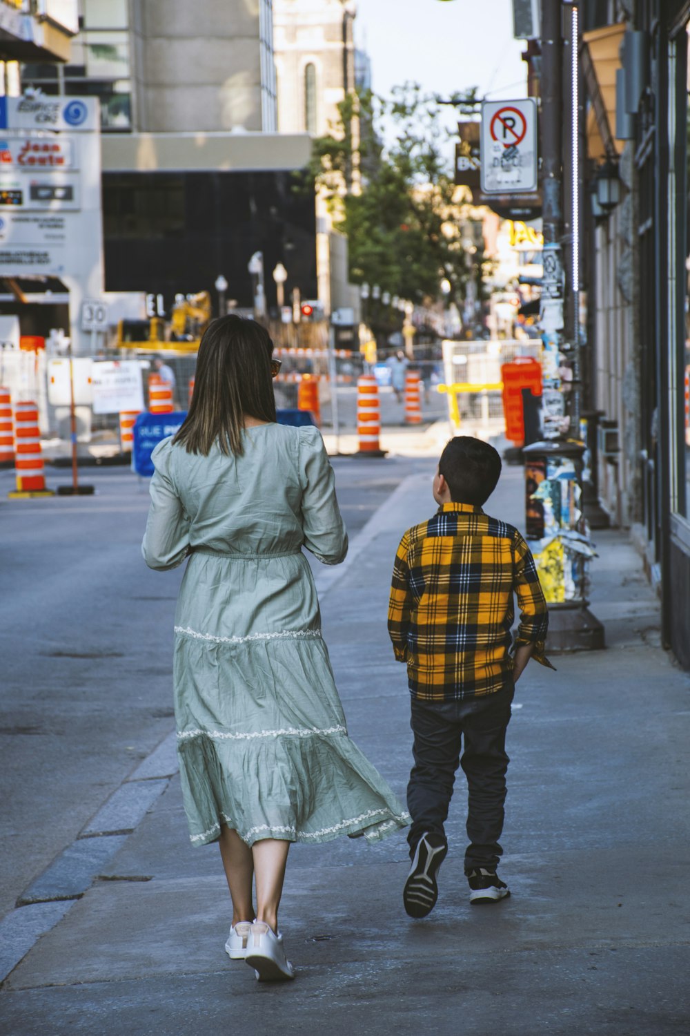 a person and a child walking down a sidewalk