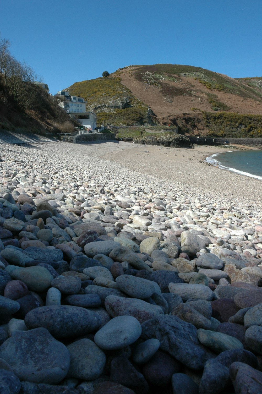 a rocky beach with a building in the distance