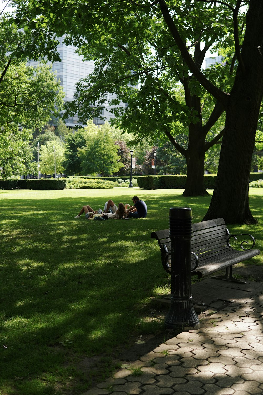 a couple of people lying on a bench in a park
