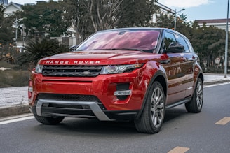 a red range rover parked on the side of the road