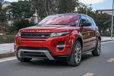 a red range rover parked on the side of the road