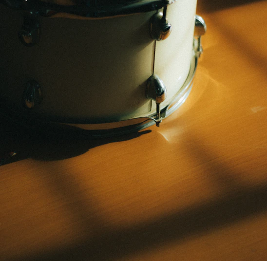 Close-up of a handcrafted mandar drum resting on terracotta red soil, bathed in warm natural light.