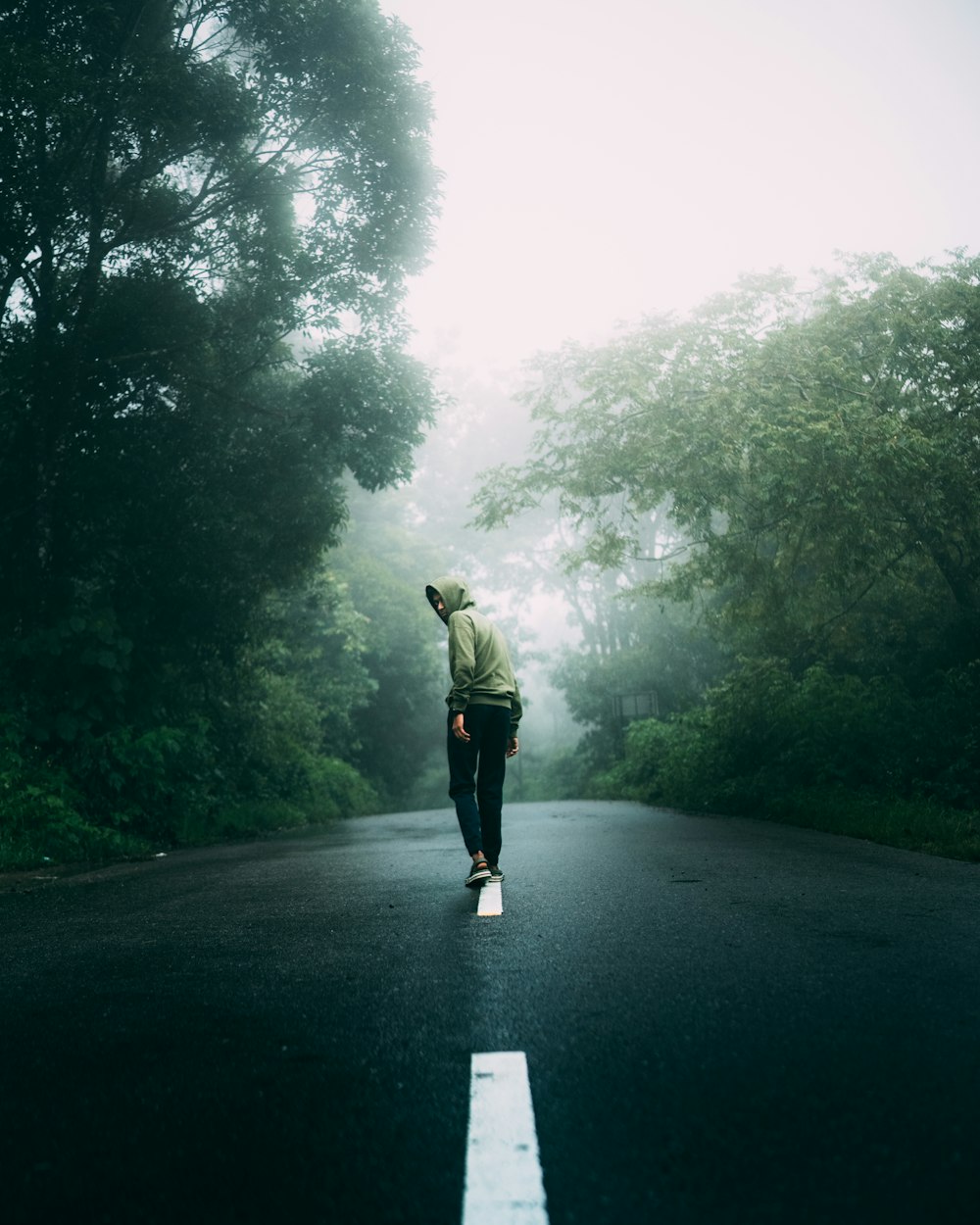 a person standing on a road with trees on either side of it