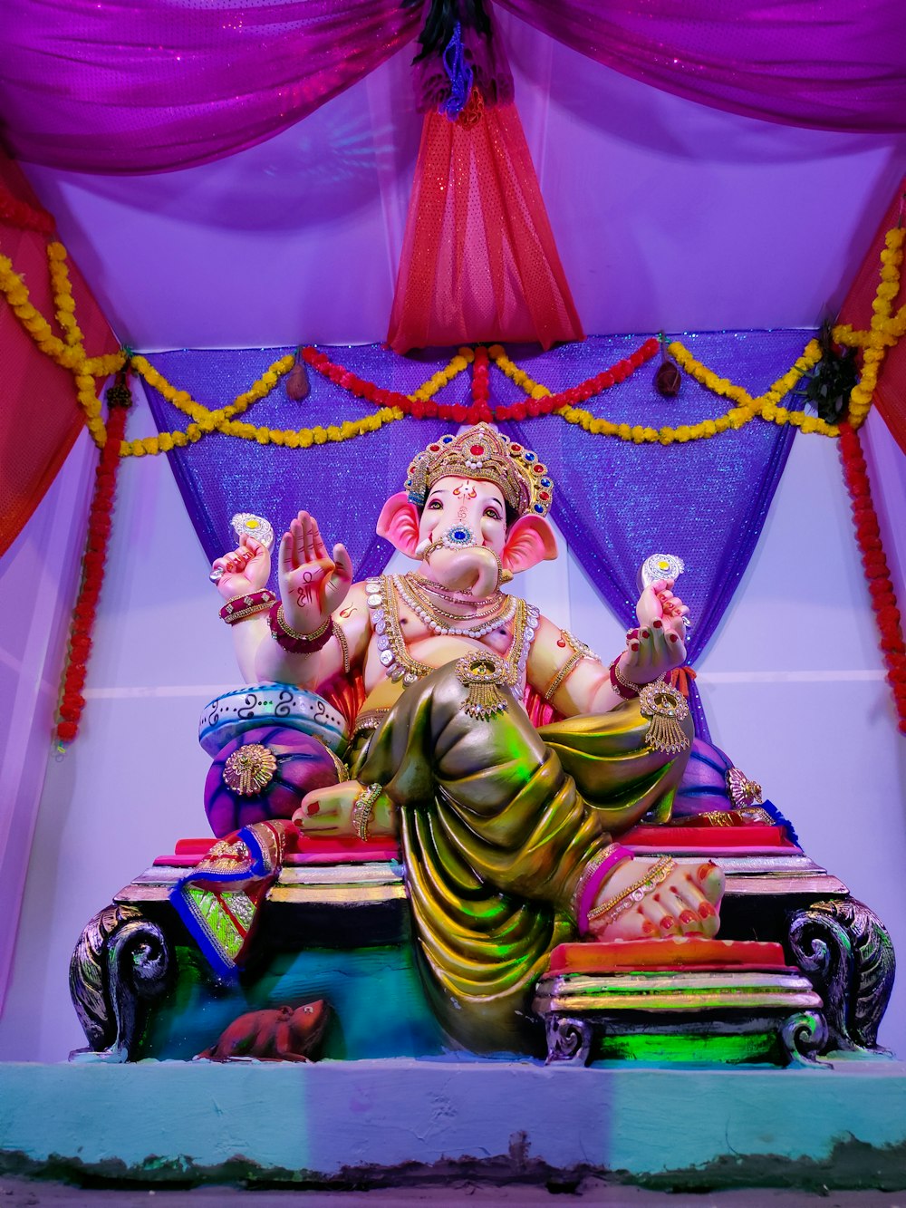 a statue of a person sitting on a throne with a colorful background