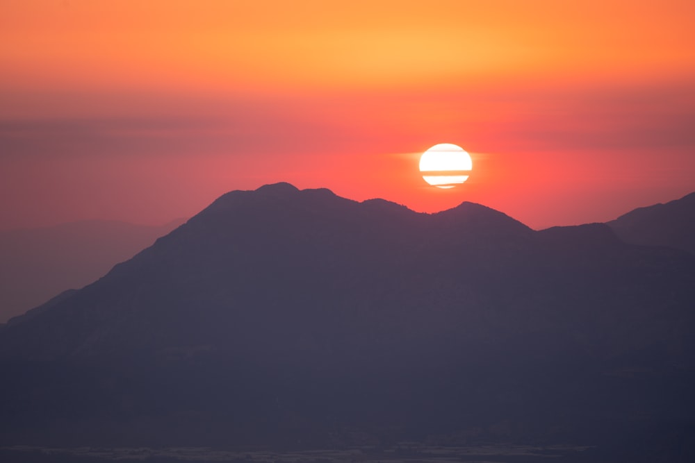 a mountain with the sun in the background