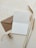 An open blank card and a brown envelope are placed on a textured surface alongside a spool of string and three stalks of wheat.