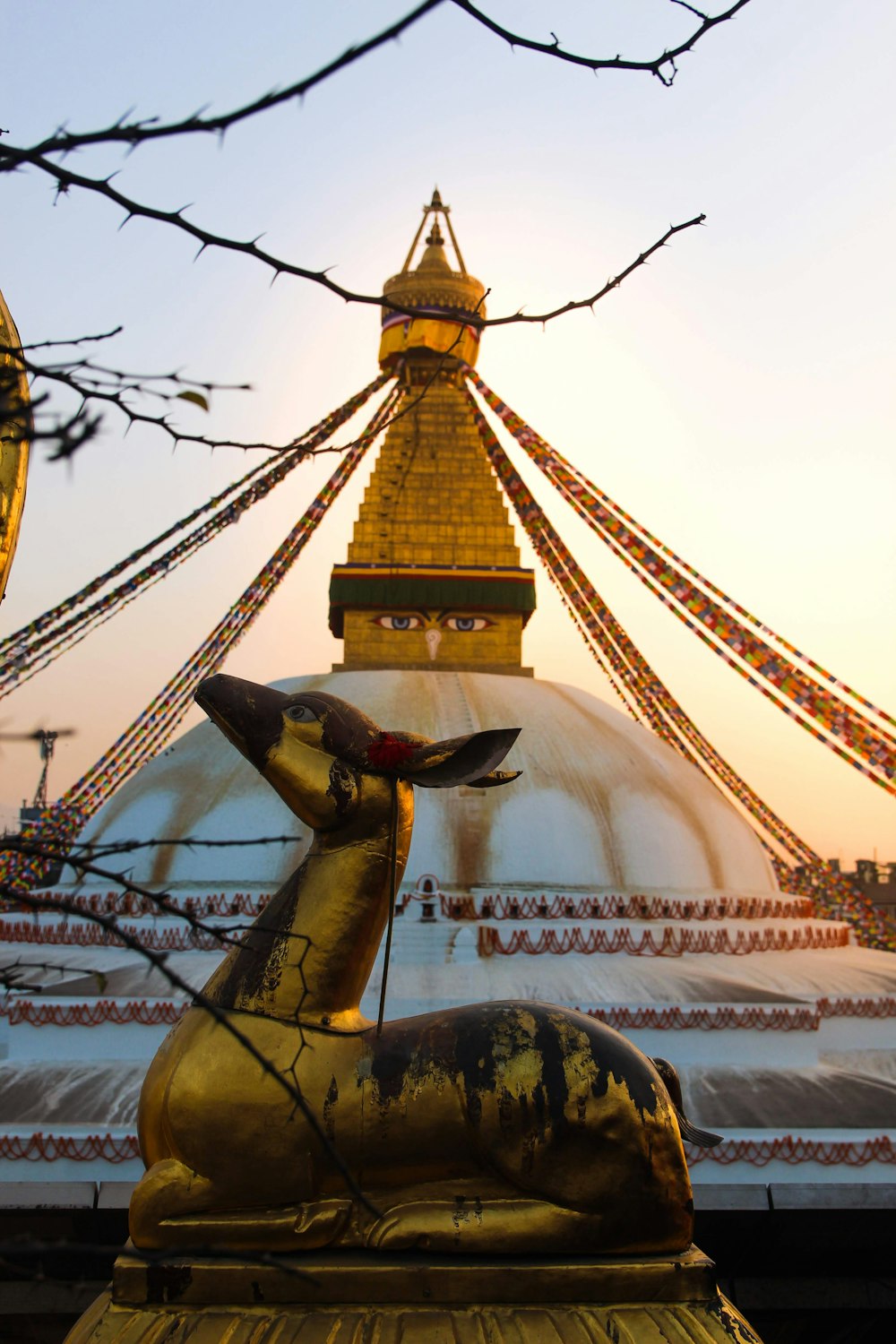 a gold and red tower with Boudhanath in the background