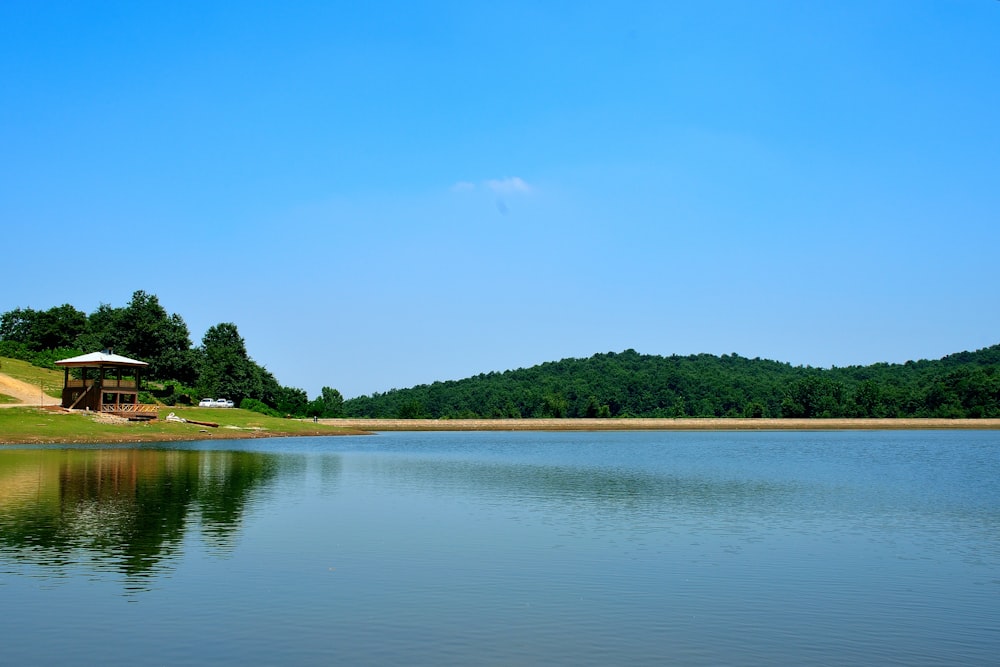 a body of water with trees and a gazebo in the background