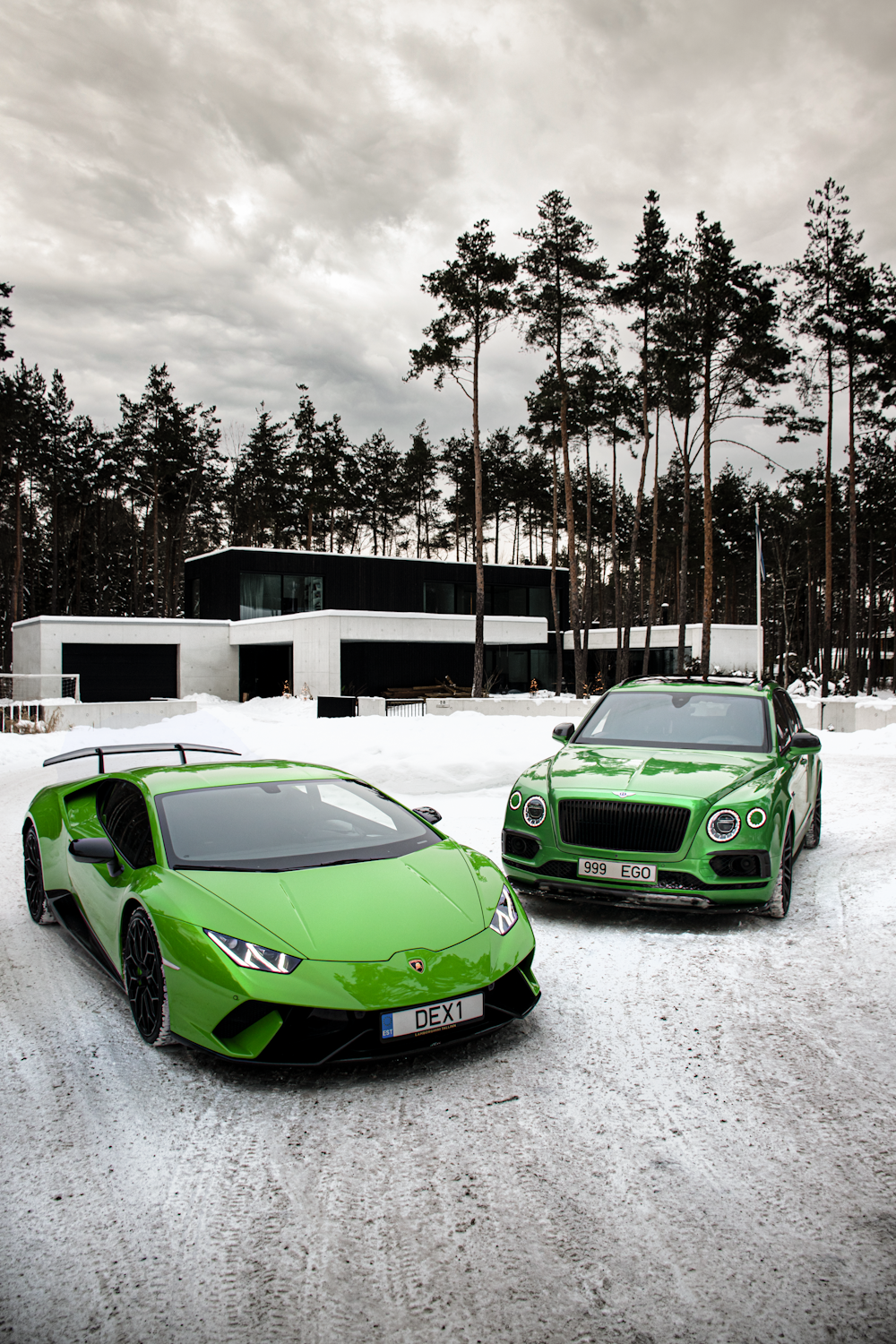 two green cars parked in a snowy parking lot