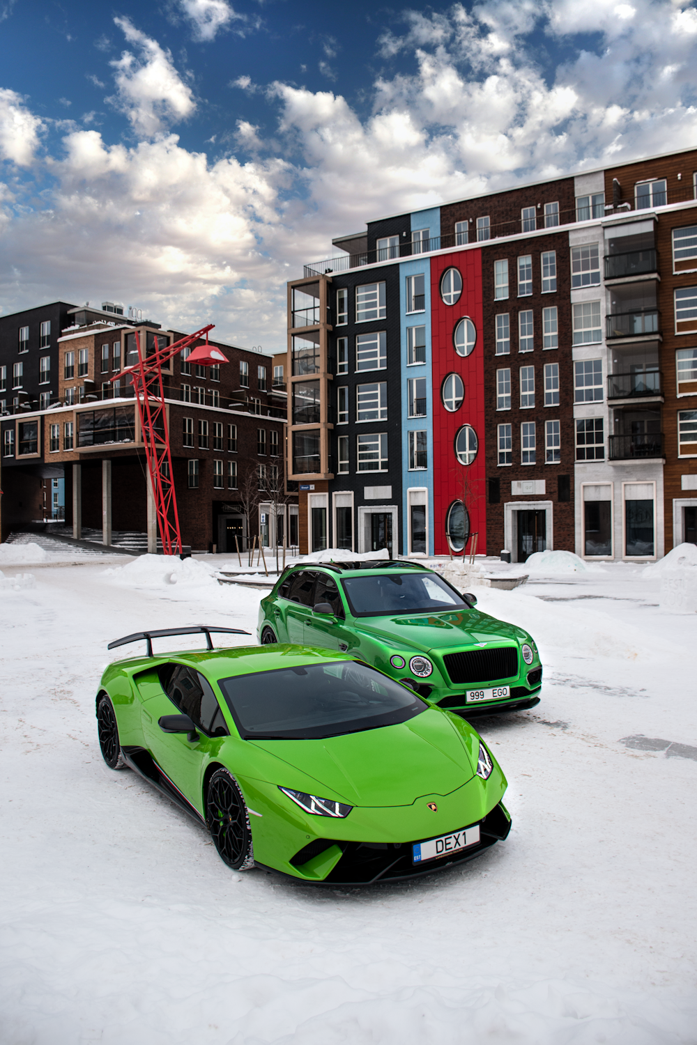 a couple of cars parked in a snowy parking lot by a building