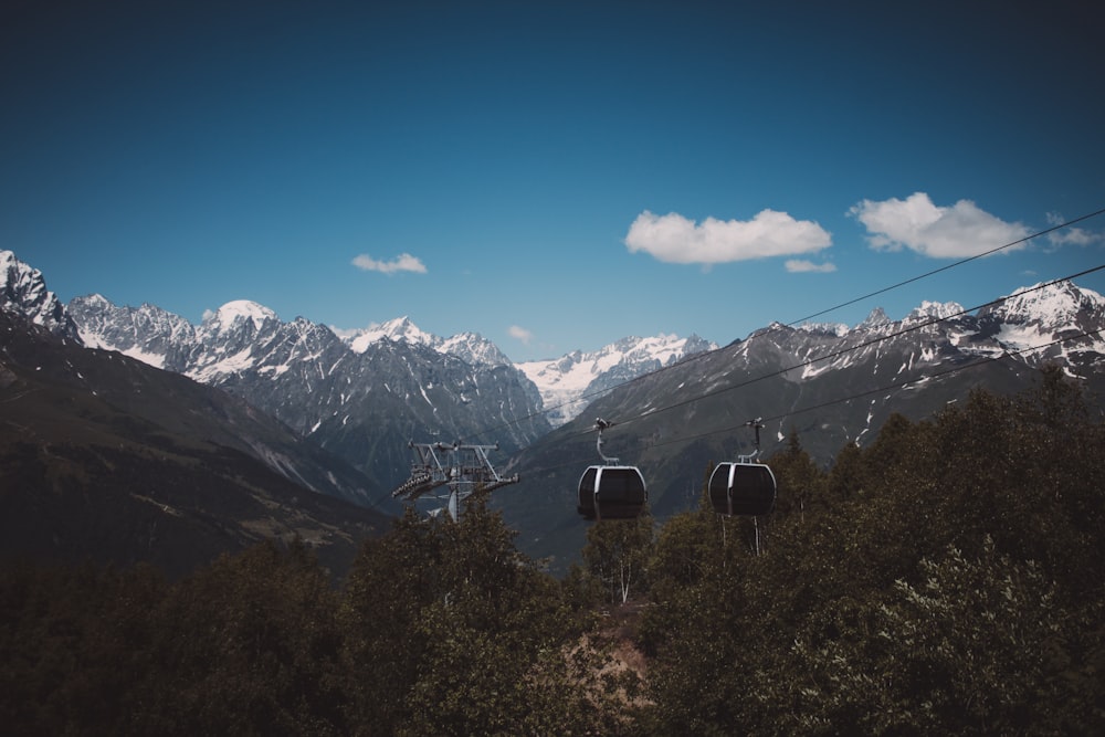 a couple of chairs on a cable car above a mountain range