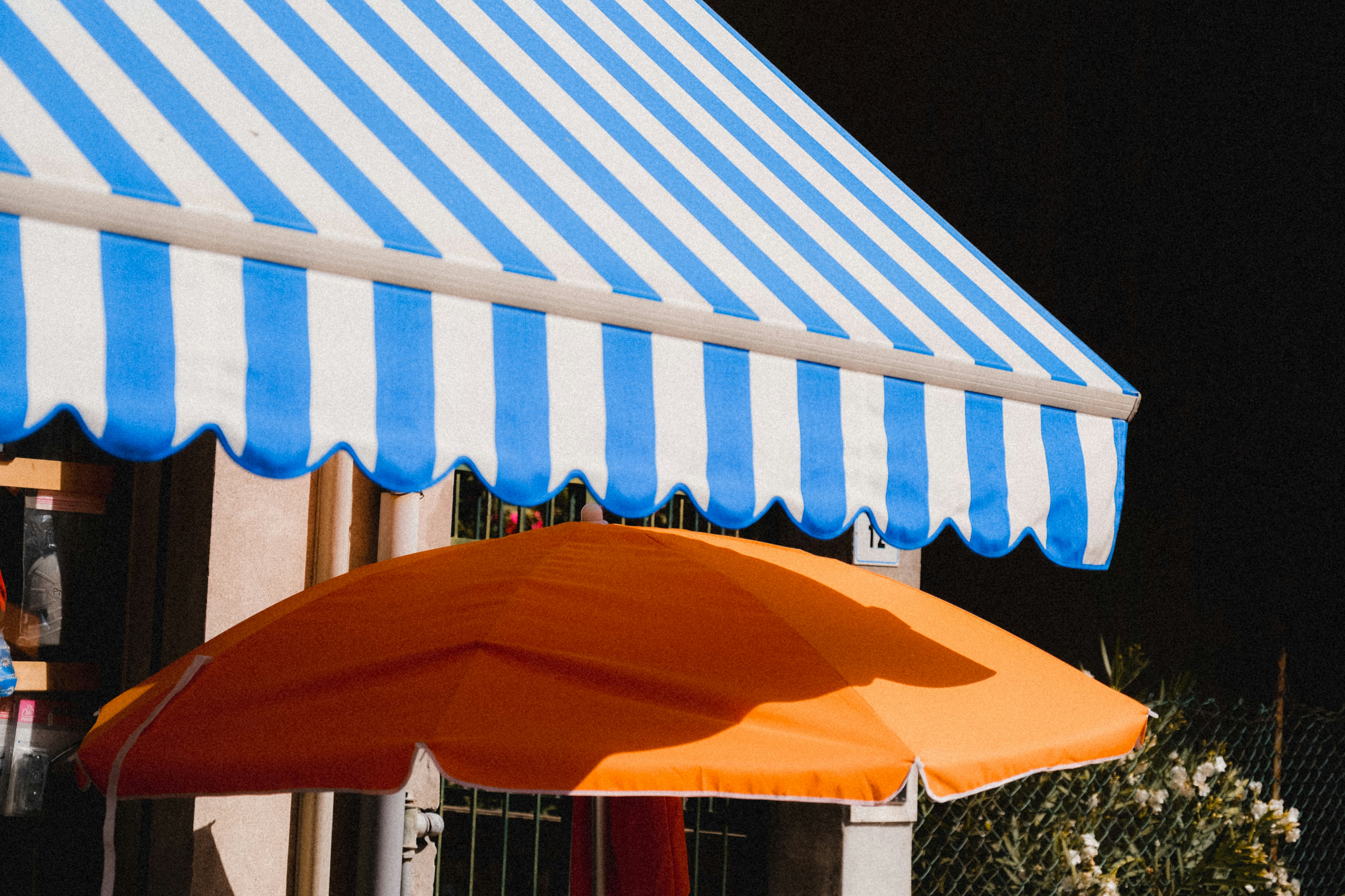 Blue-and-white striped awning above an orange umbrella