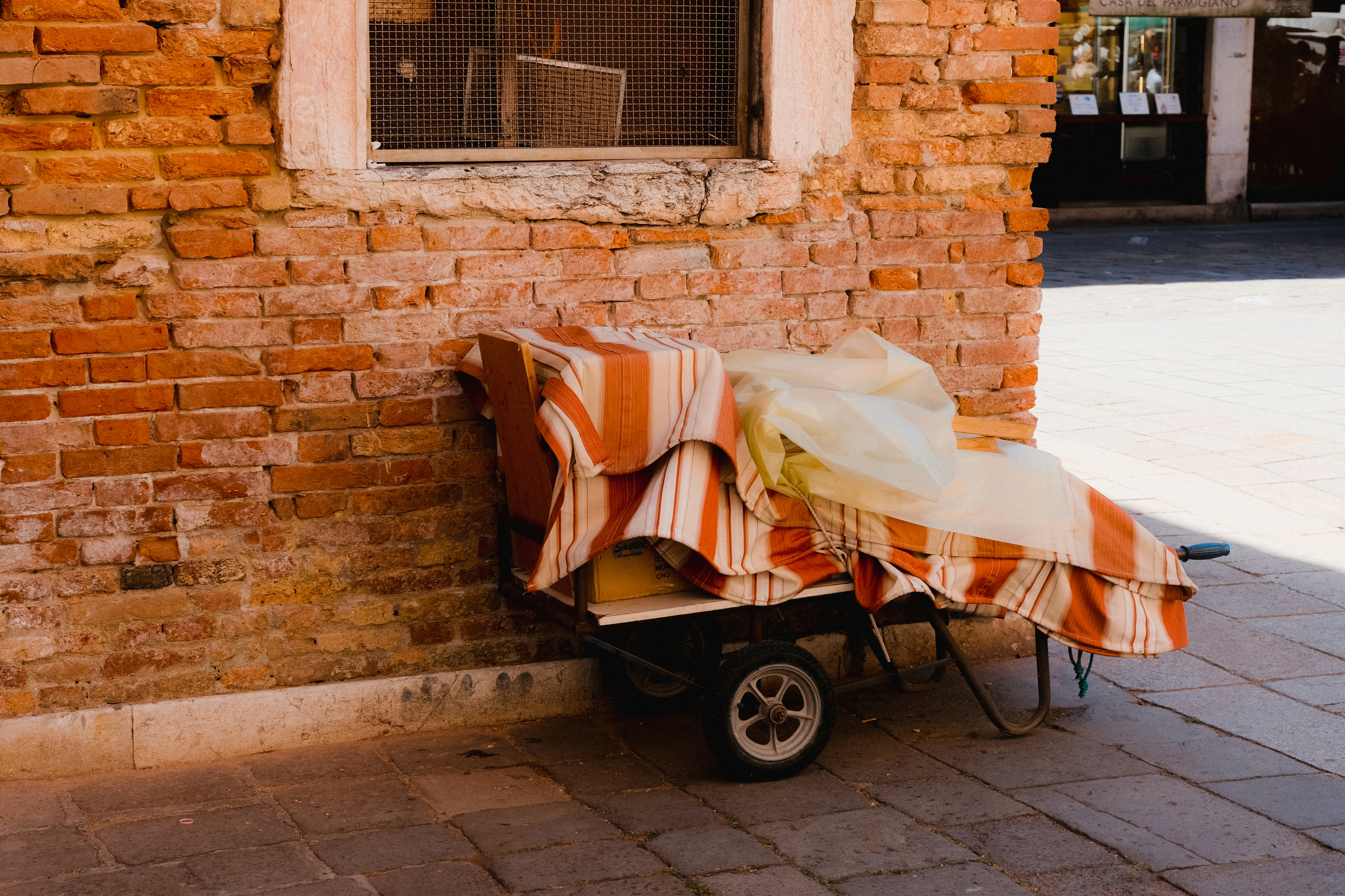 Hand cart covered with a blanket by a brick wall