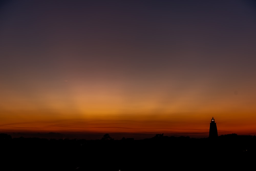 a silhouette of a lighthouse at sunset