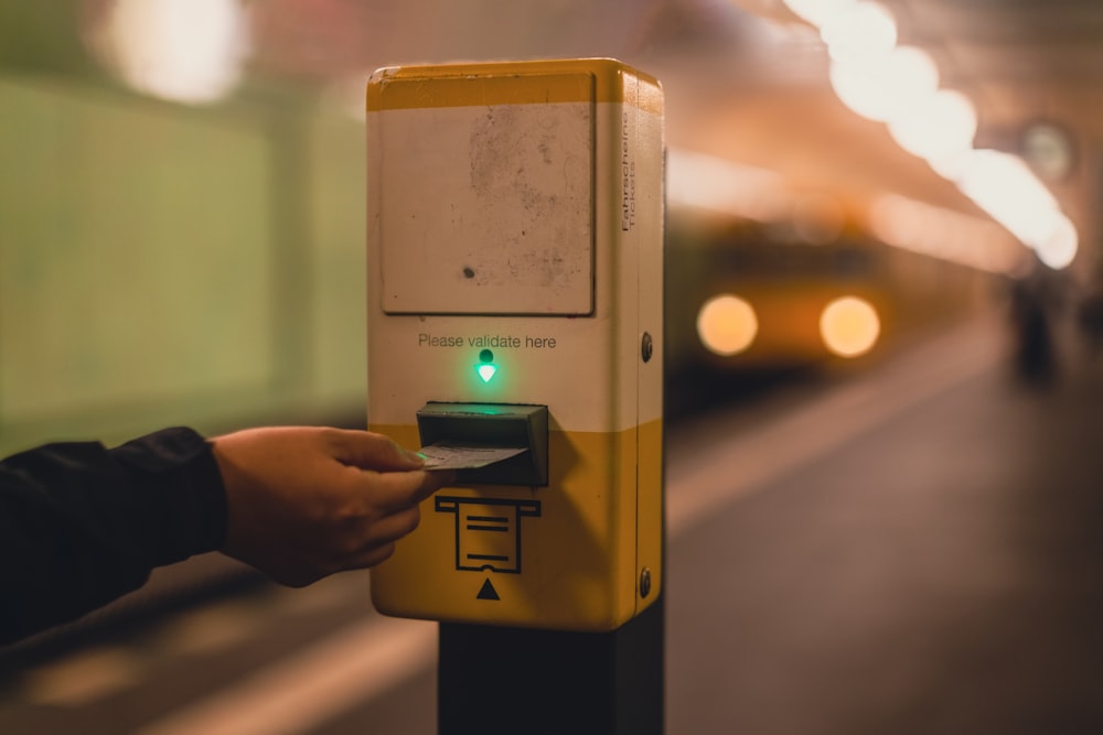 a hand holding a yellow and black box with a black and white logo