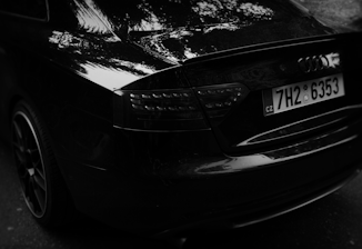 Close-up of a rose gold license plate frame reflecting soft light on a sleek black car surface.