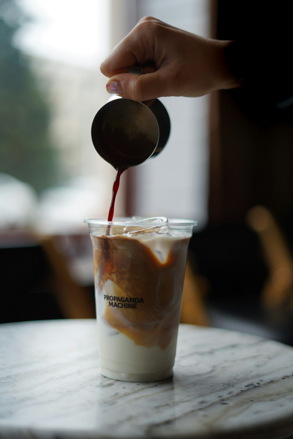 a hand holding a glass with a drink in it