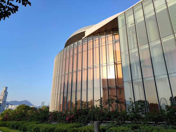 Finished modern building with reflective glass and metallic gold accents glowing in sunset light.