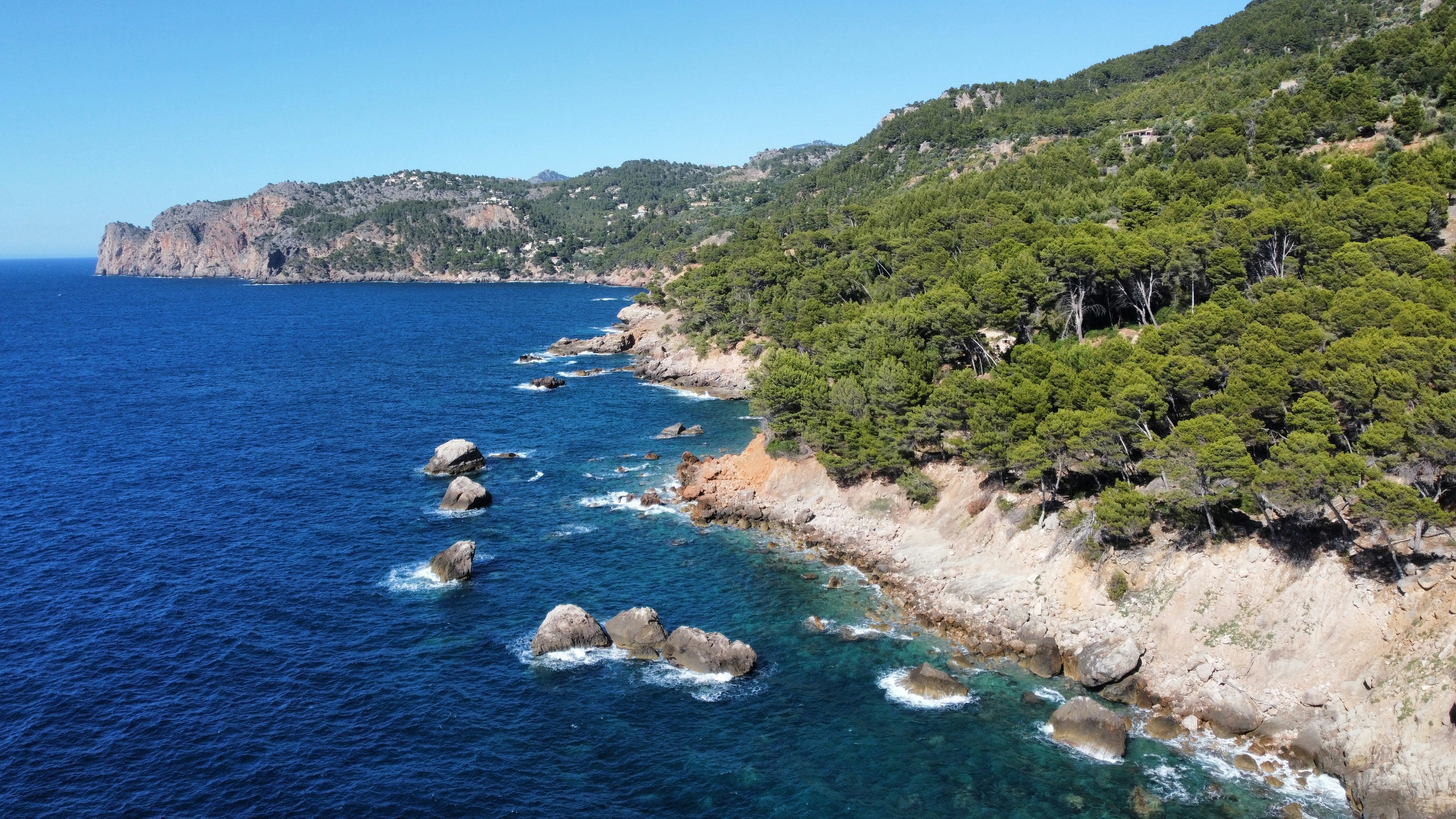 a rocky beach with trees and hills