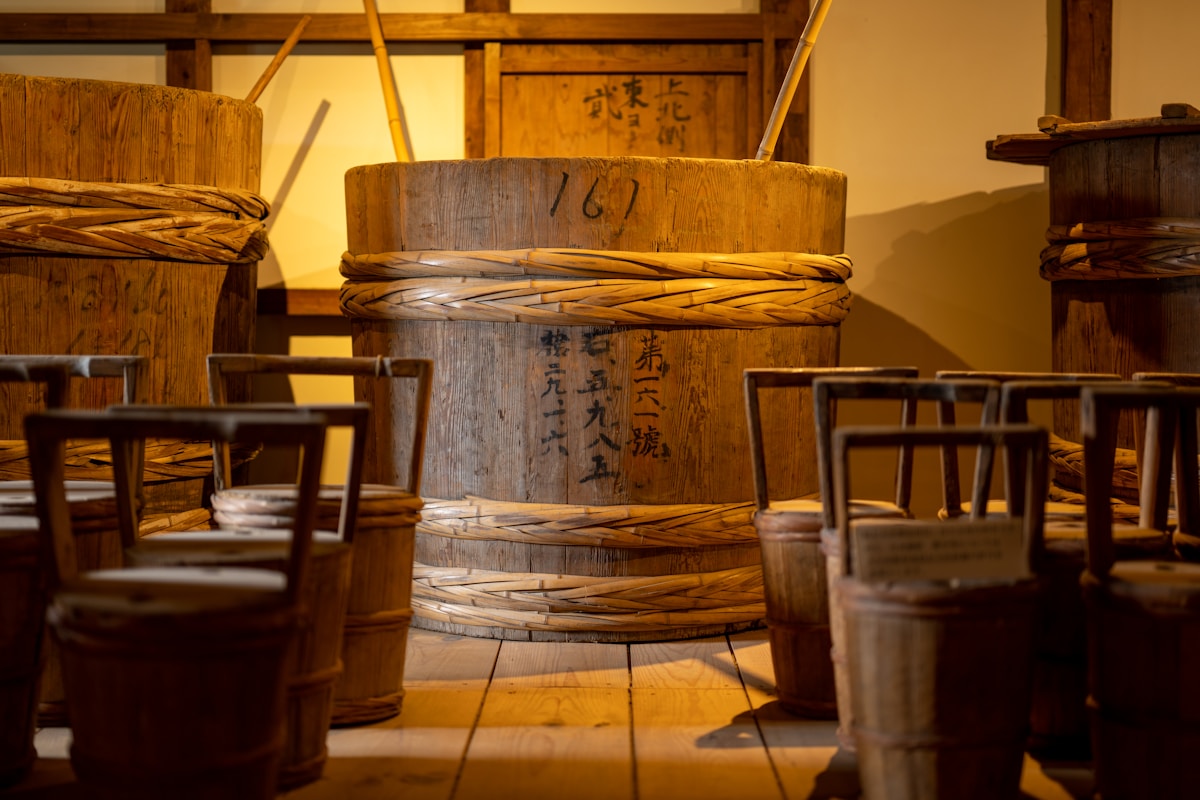 Japanese whisky barrels in dim warehouse, deep amber and wood tones