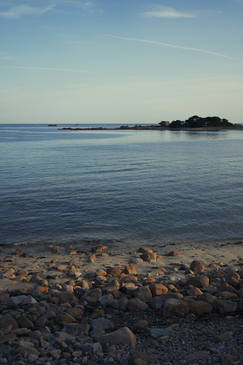 a rocky beach with a body of water in the background