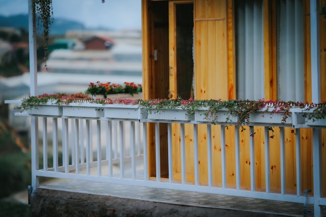 A wooden balcony overlooking terraced hills and lush avocado trees at sunset.