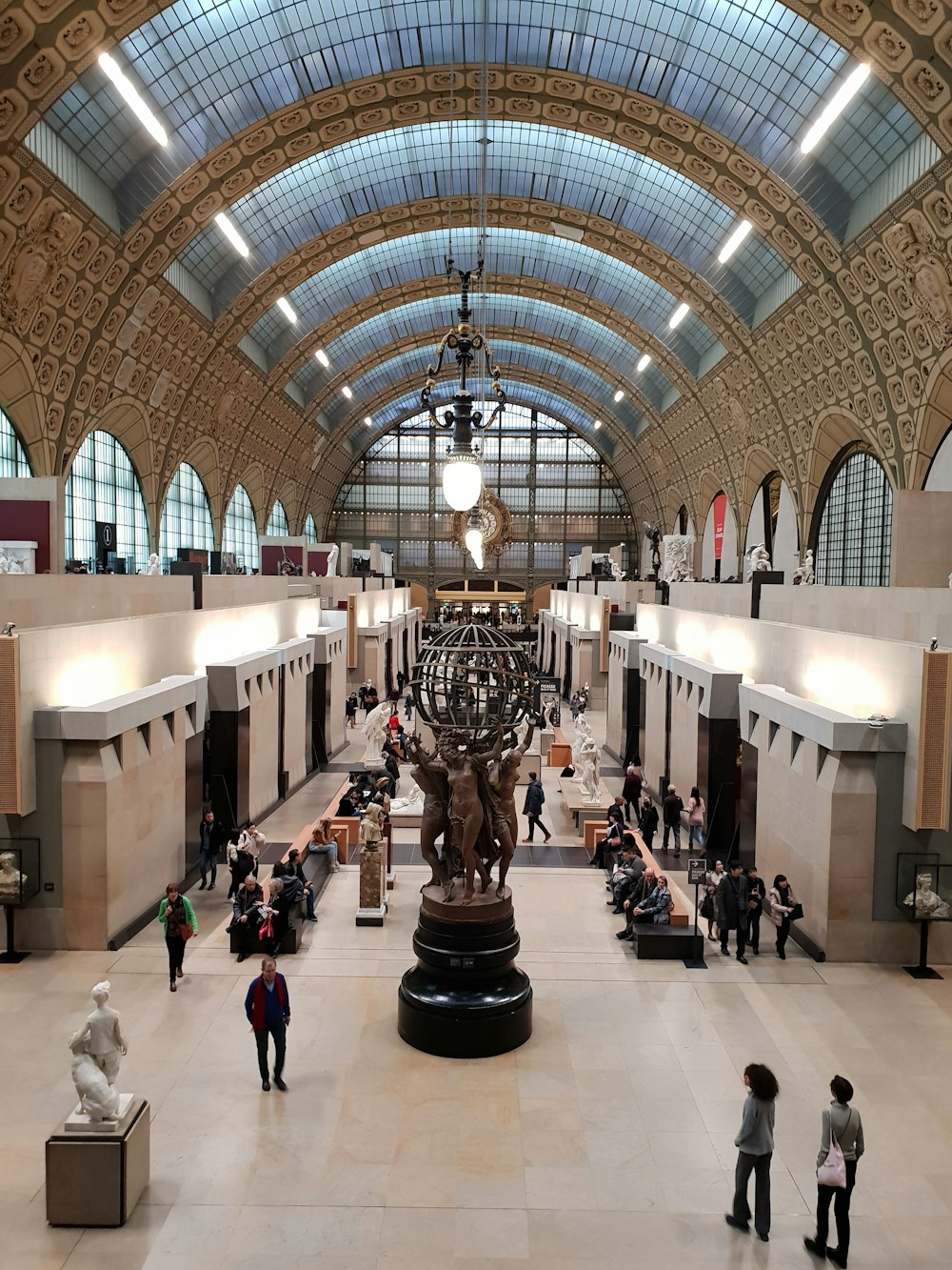 a large room with people and statues with Musée d'Orsay in the background