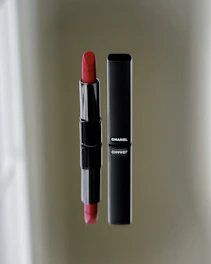 Matte black compact case opened to reveal a rich, velvety red lipstick inside.