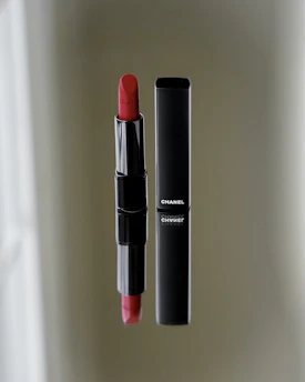 Matte black compact case opened to reveal a rich, velvety red lipstick inside.