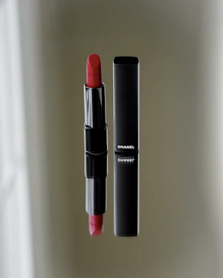 A close-up of hands applying a popular branded lipstick from the luxelingerie collection.