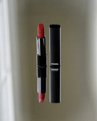 Elegant matte black compact with rich red lipstick beside it on a black velvet cloth