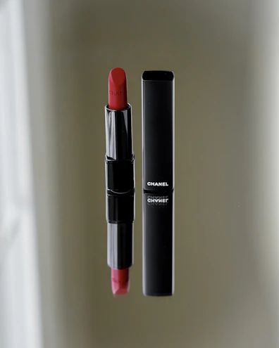Elegant matte black compact with rich red lipstick beside it on a black velvet cloth