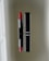 A vibrant red lipstick stands next to its sleek black case on a reflective surface. The brand name is visible on the case, emphasizing luxury and elegance.