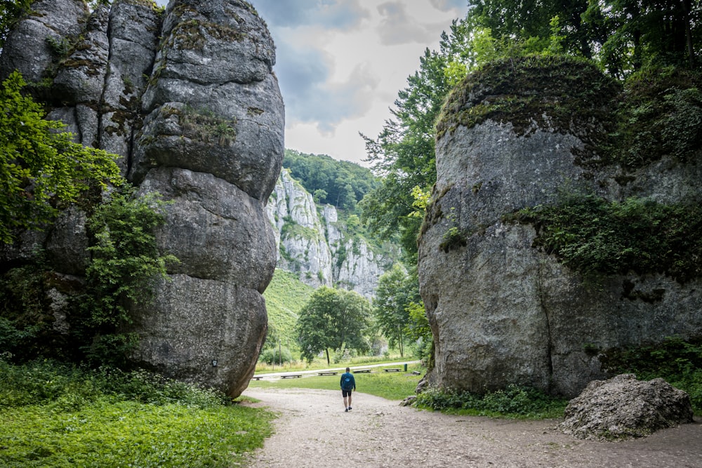a person walking on a path between large rocks