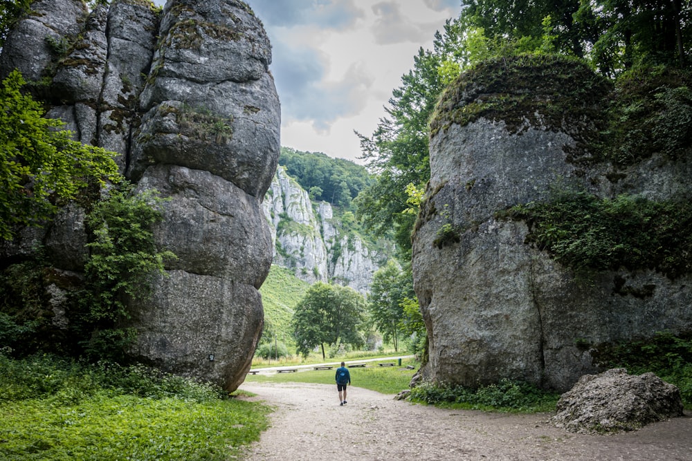 una persona caminando por un sendero entre grandes rocas