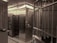 An interior space dominated by metal surfaces and structures, resembling a vault or secure facility. The walls and door are made of metal, with visible rivets and steel bars forming a secure area. There are numbered boxes on the left, possibly indicating storage or safety deposit boxes, and a shelf with a small object or item placed on it.