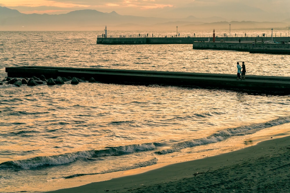 a couple of people standing on a dock over water