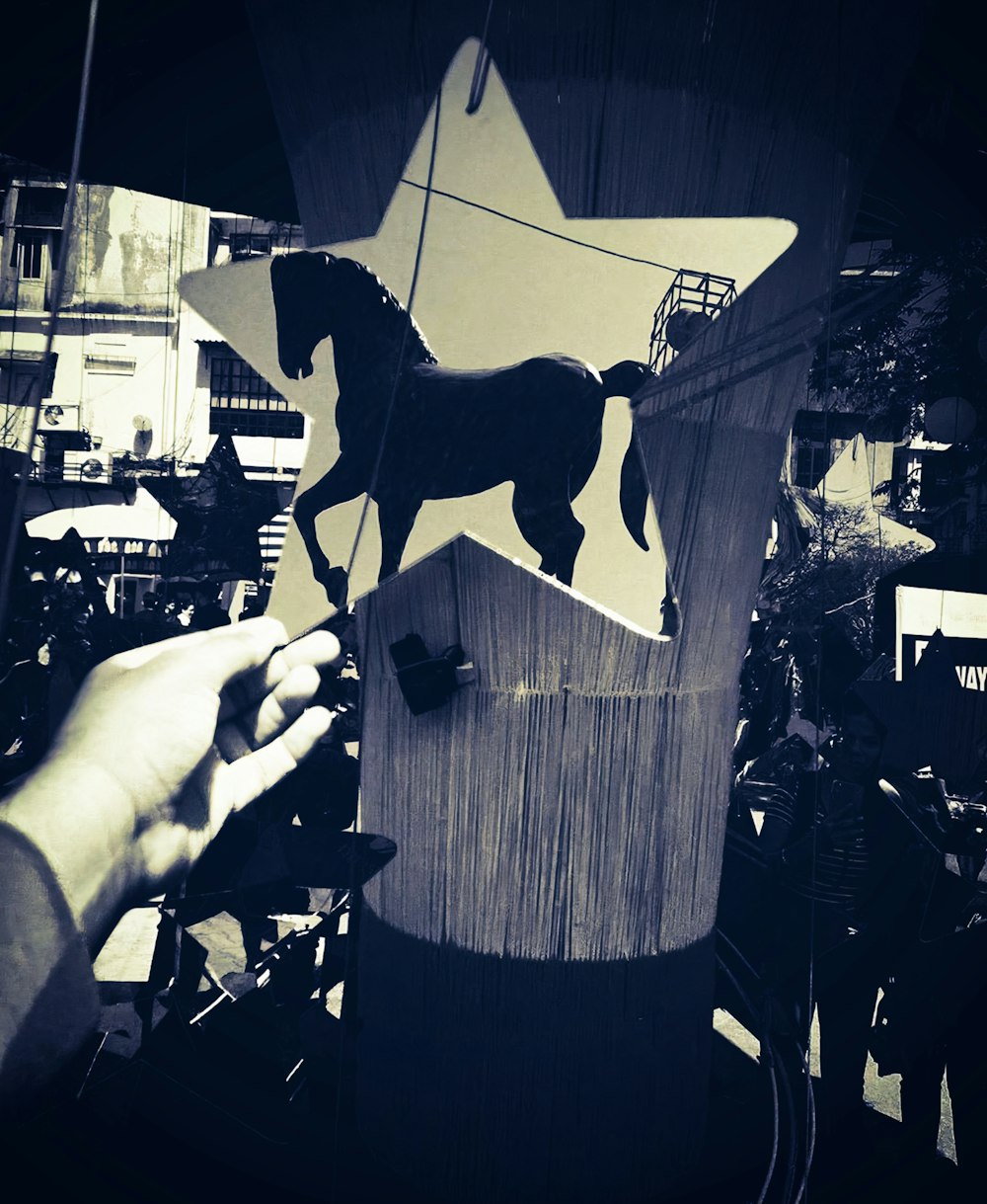 a person holding a wooden object with a horse on it