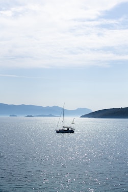 A serene yacht gliding smoothly over calm blue waters under a bright sunny sky.