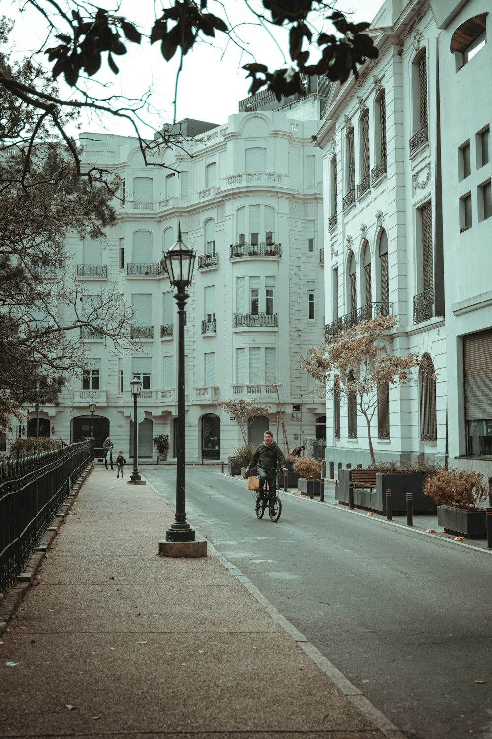 a person riding a bicycle on a street between buildings