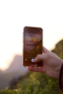 A travel influencer capturing a scenic coastal sunset with a branded product in hand.