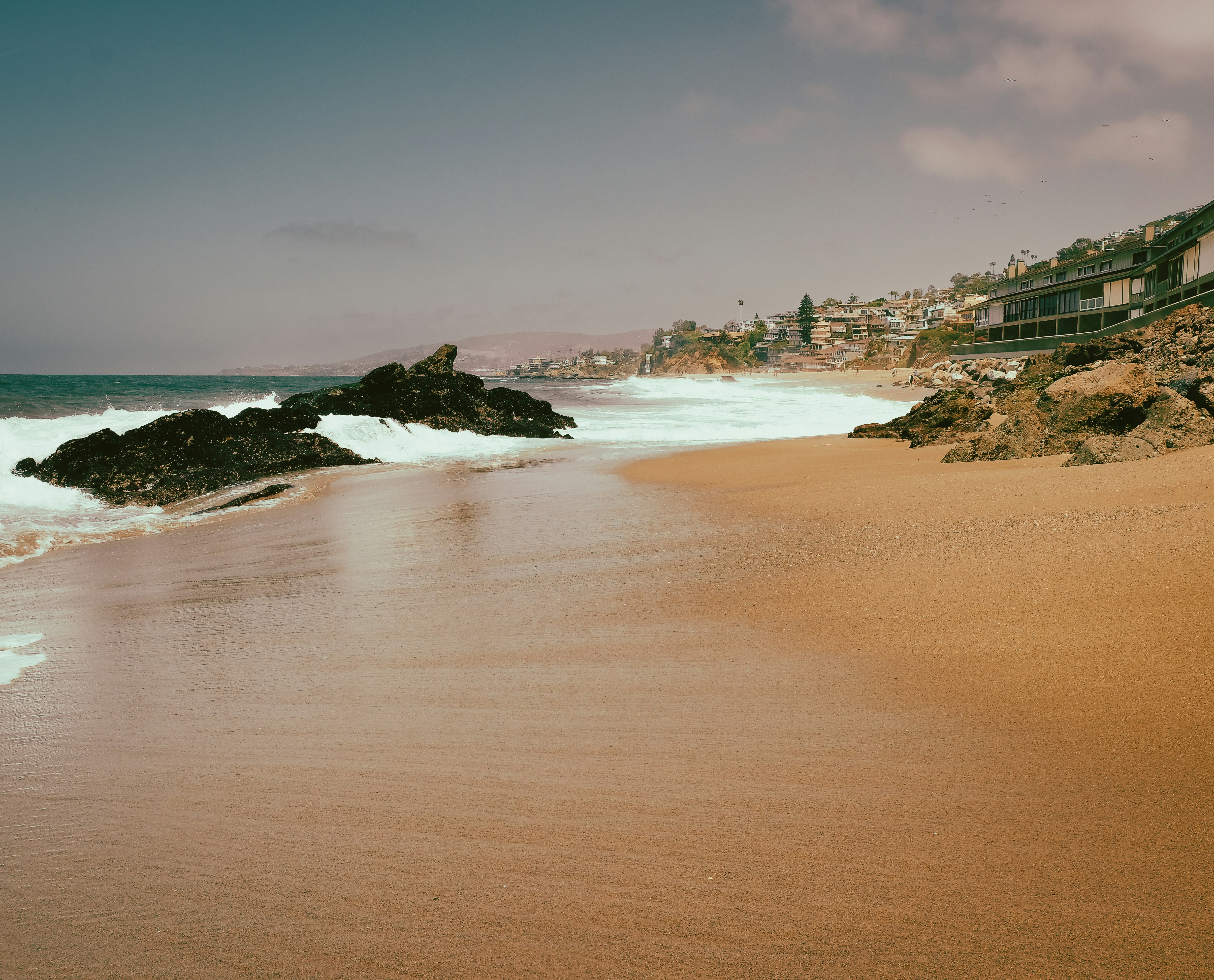 a sandy beach with a building on the shore