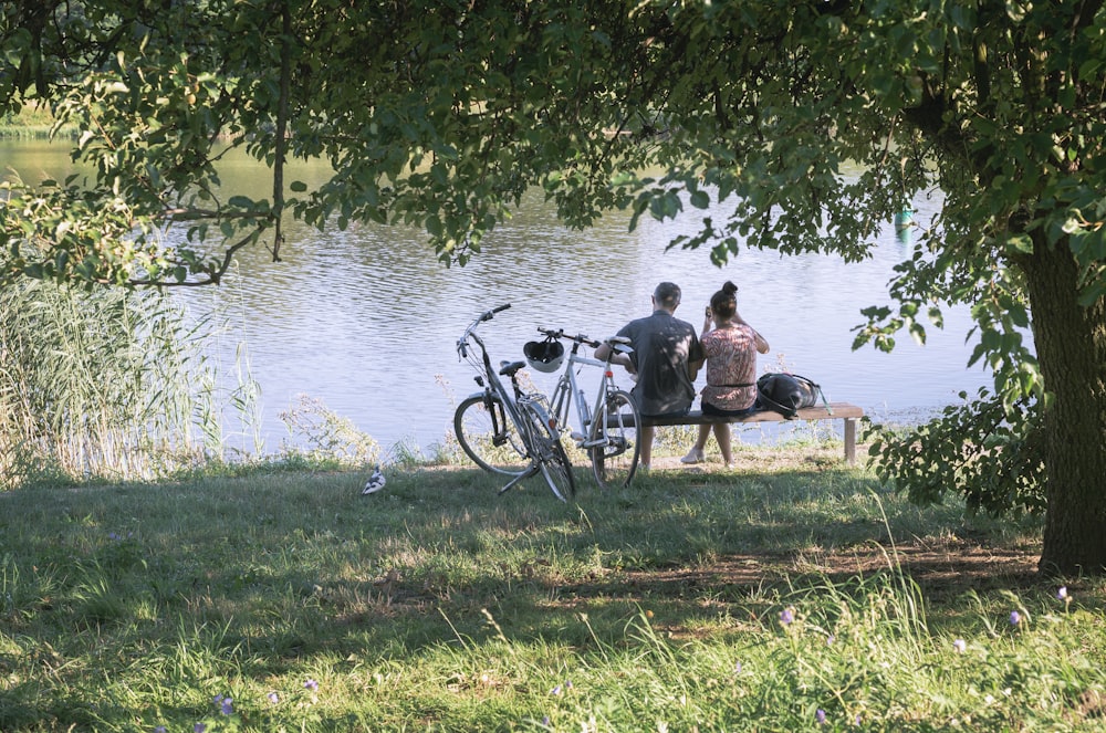 a couple sitting on a bench next to a lake