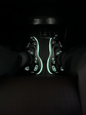 Close-up of electric cyan and neon pink sneakers glowing under blacklight.