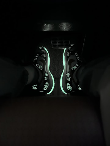 Close-up of colorful neon sneakers glowing under blacklight.